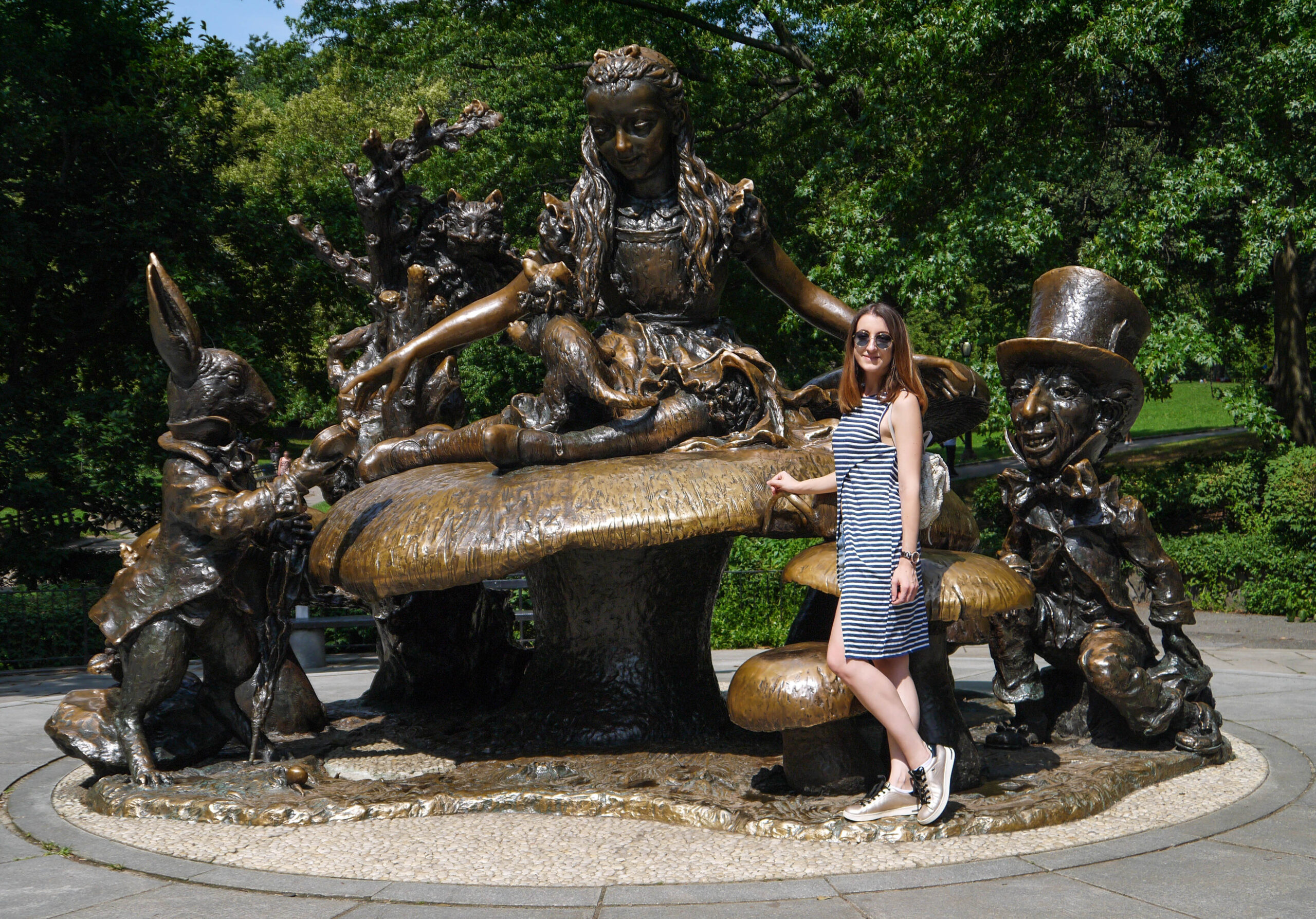 Girl in front of a bronze sculpture of Alice in Wonderland