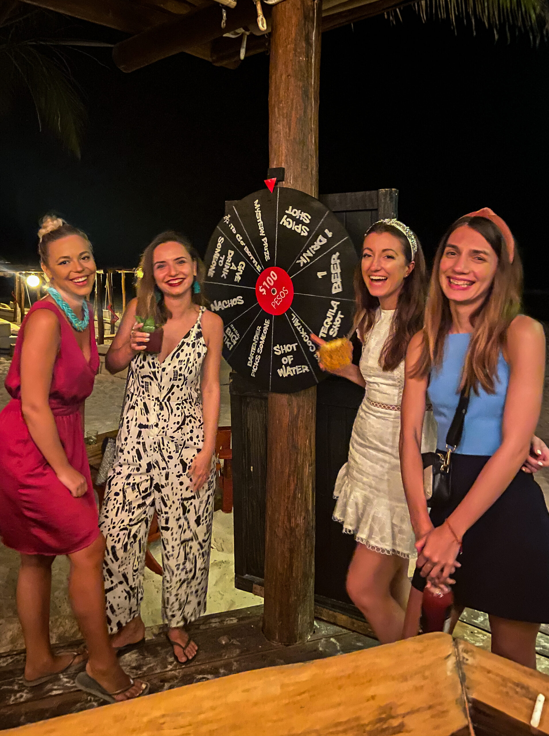 Four girls at a beach bar playing spin the wheel La Zebra Tulum