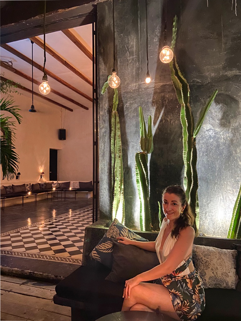 Girl sat in a courtyard with lights and cacti Gitano Tulum